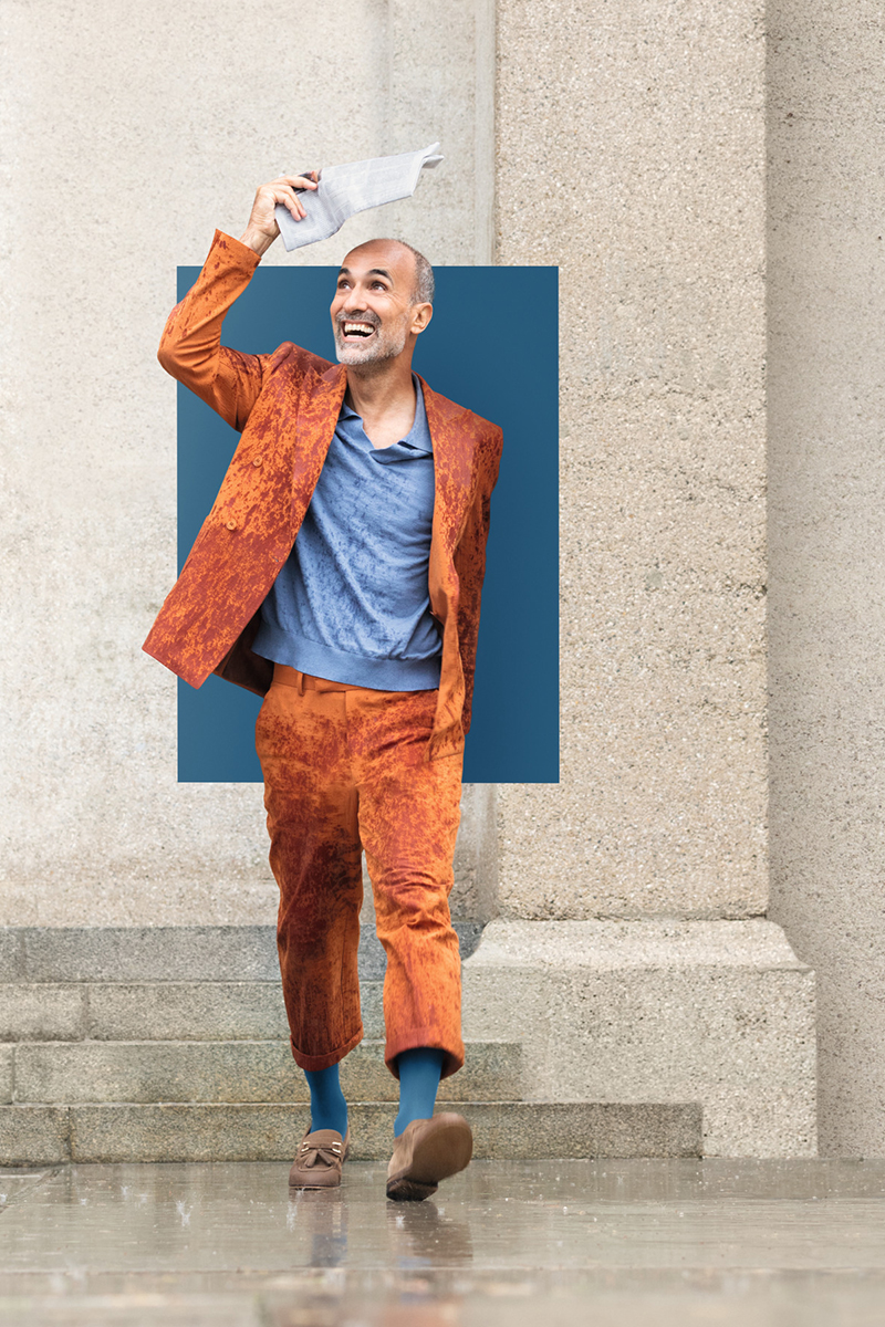 Mann sitzt auf einer Treppe. Er trägt blaue Kompressionsstrümpfe. Im Hintergrund ein Farbfeld in der aktuellen Trend Farbe Casual Blue Mann sitzt auf einer Treppe. Er trägt blaue Kompressionsstrümpfe. Im Hintergrund ein Farbfeld in der aktuellen Trend Farbe Casual Blue