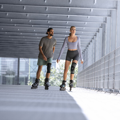 Ein Mann und eine Frau mit einer Kniebandage fahren Inliner in einer Garage