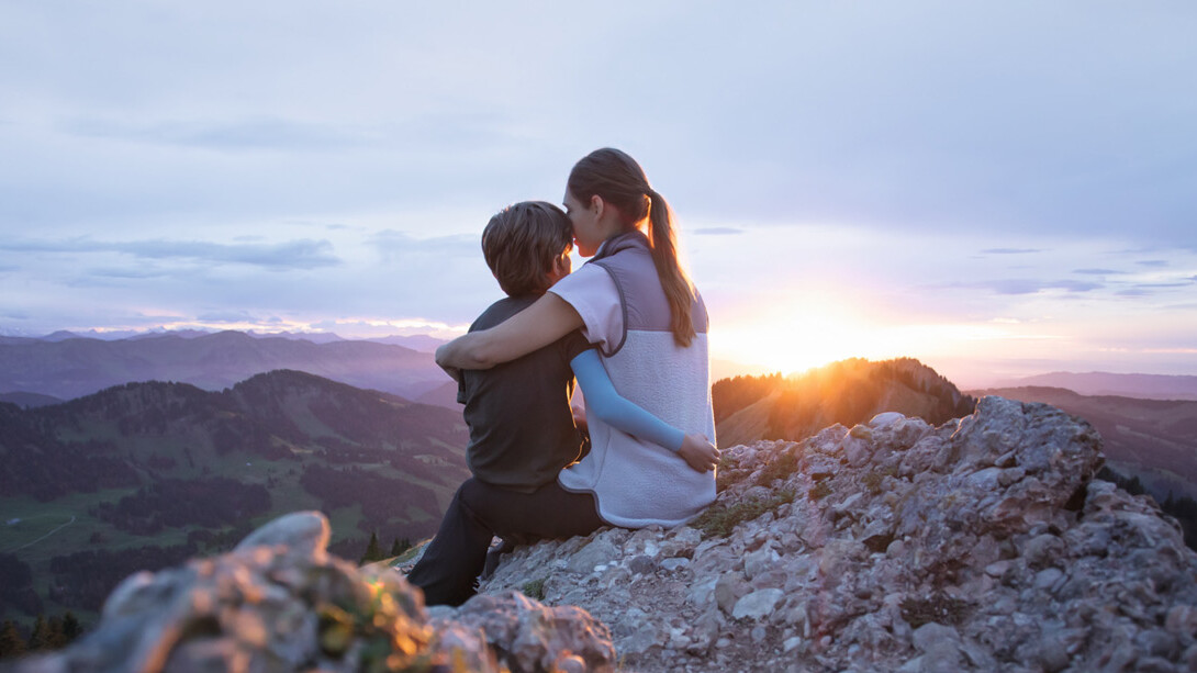 Une mère est assise avec son enfant au sommet d'une montagne. L'enfant porte une manchette de compression.