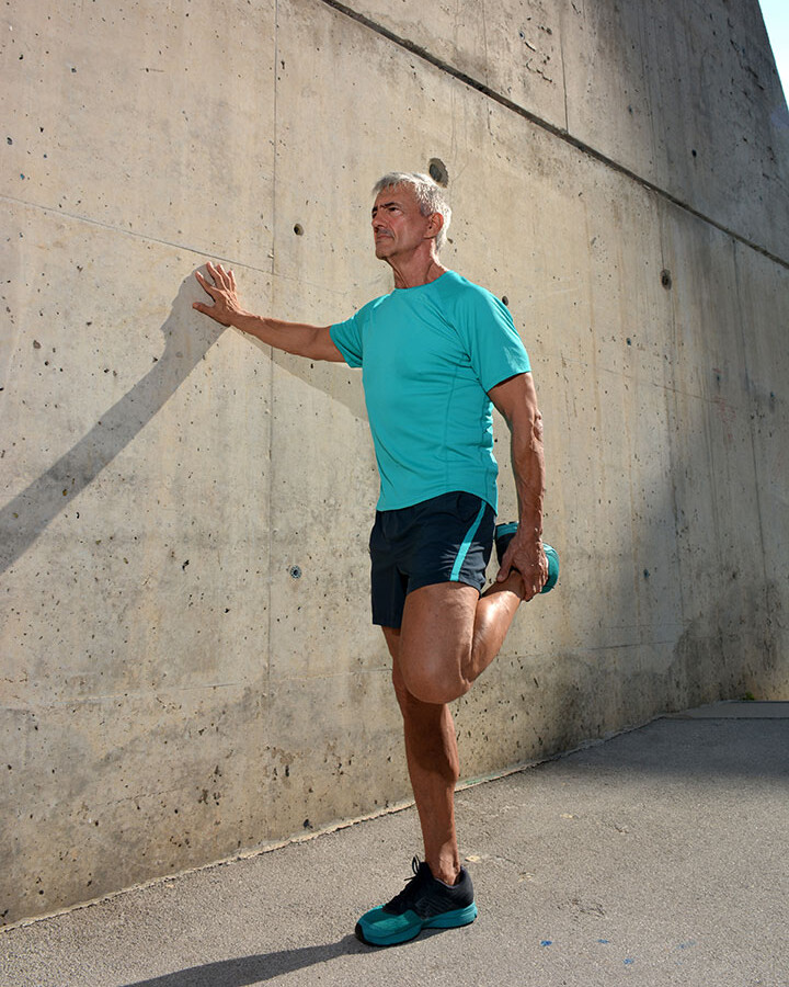 A man leans against the wall and stretches his quadriceps A man leans against the wall and stretches his quadriceps