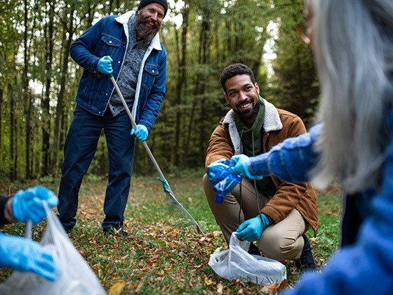 Müll sammeln kann jeder Drei Männer sammeln Plastikmüll in einem Wald