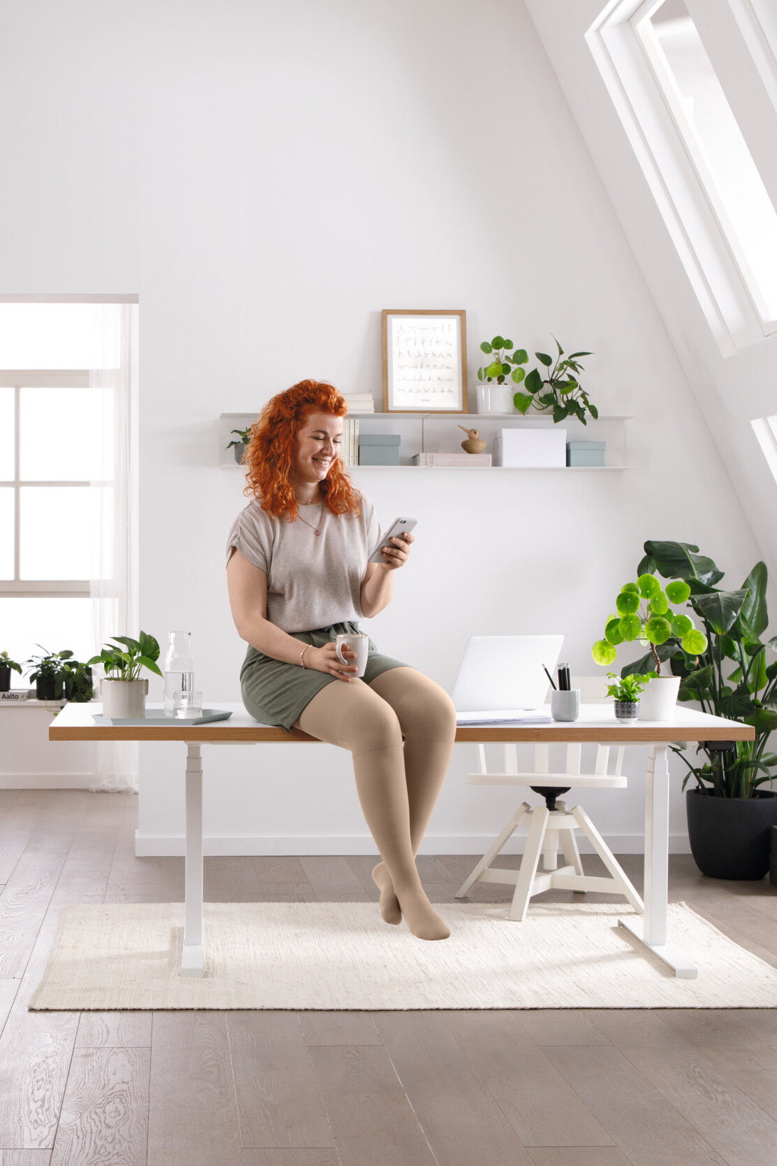 Kobieta siedzi przy biurku i czyta coś na telefonie komórkowym Kobieta siedzi przy biurku i czyta coś na telefonie komórkowym