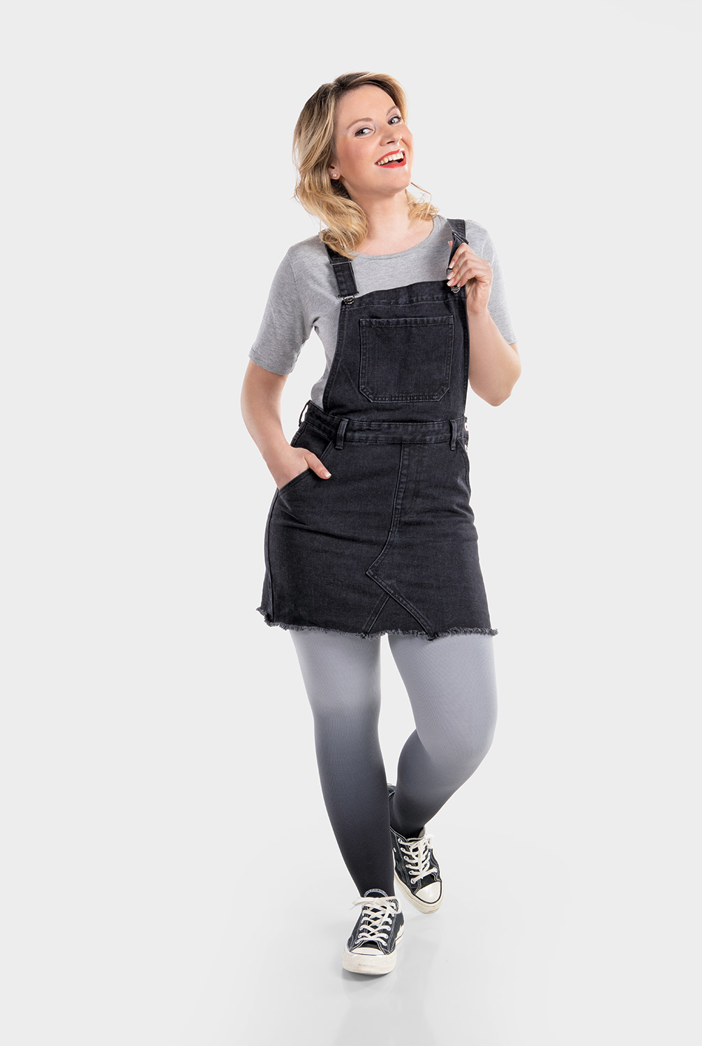 Eine Frau trägt ein schwarzes Latzkleid und dazu eine Kompressionsversorgung in Dip Dye Grau Eine Frau trägt ein schwarzes Latzkleid und dazu eine Kompressionsversorgung in Dip Dye Grau
