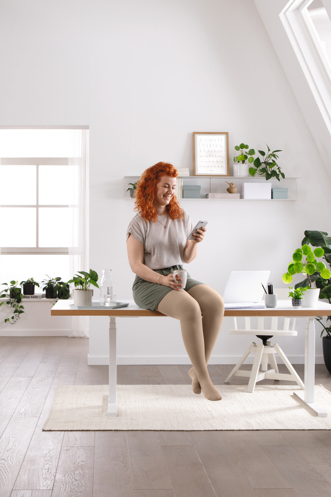 A woman is sitting at her desk, reading something on her mobile phone A woman is sitting at her desk, reading something on her mobile phone