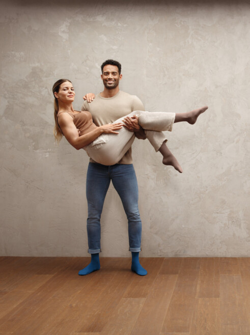 Homem com mulher nos braços, ambos com meias Juzo Intenso