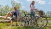 Mann und Frau mit Fahrrädern am Ufer eines Sees