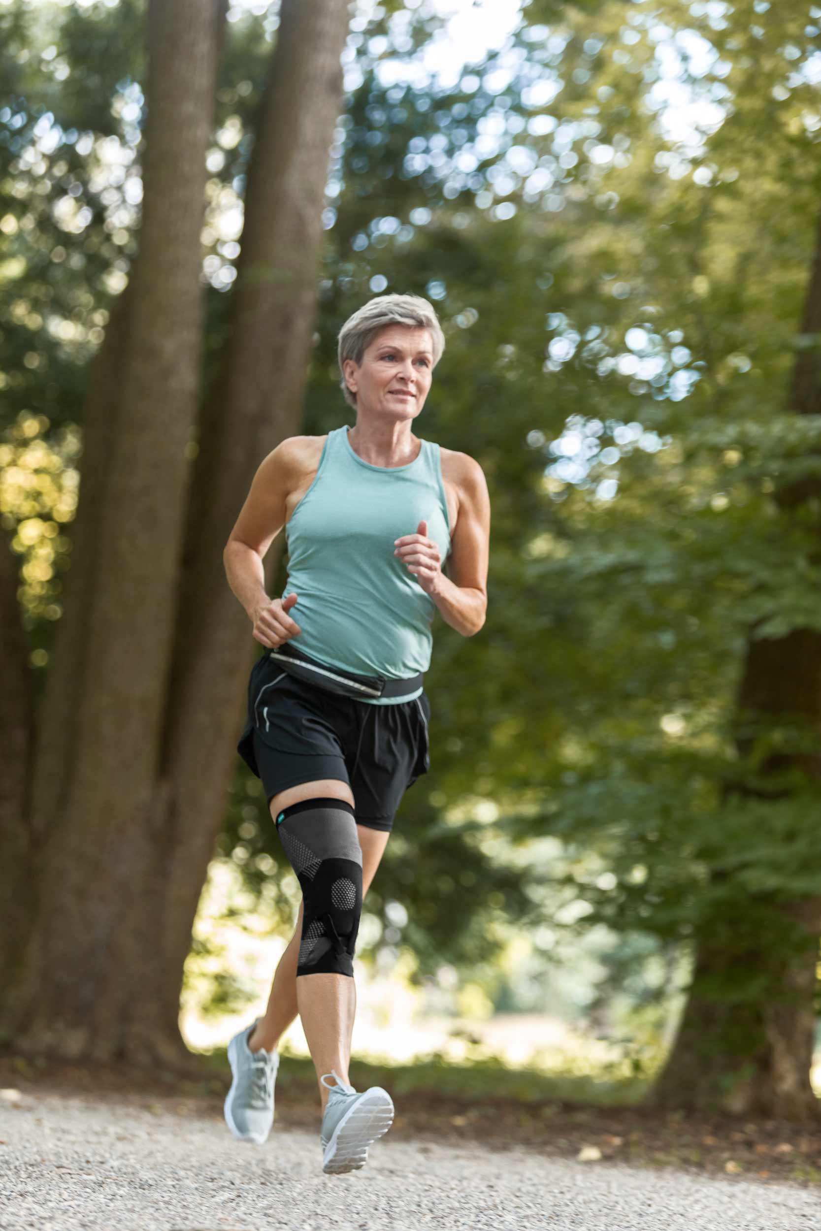 JuzoPro Patella Xtec Plus Frau im Wald beim Joggen mit Patella Xtex Plus Bandage