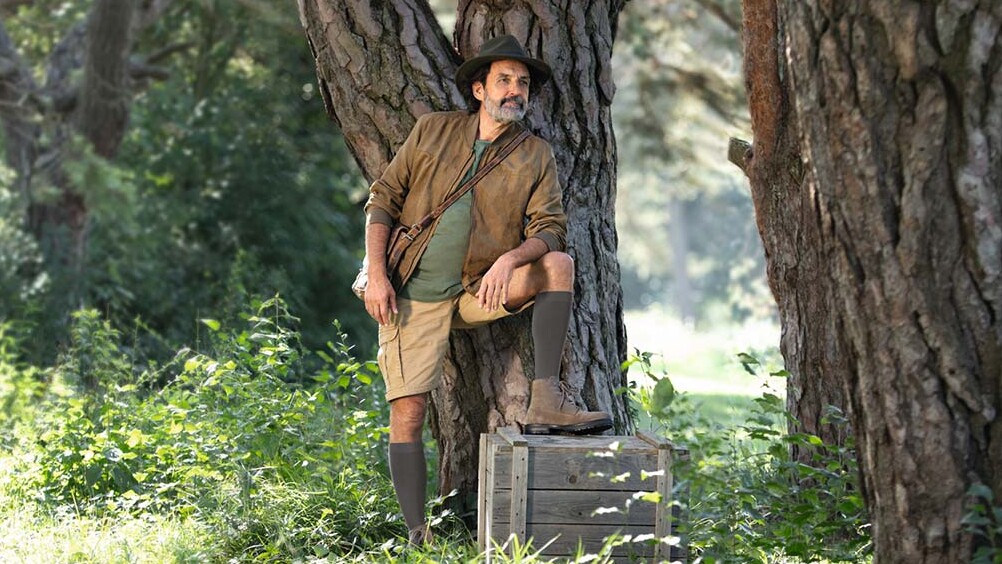 Un hombre vestido con ropa de explorador está en plena naturaleza y mira hacia el horizonte. Lleva medias de compresión que le llegan hasta las rodillas. Un hombre vestido con ropa de explorador está en plena naturaleza y mira hacia el horizonte. Lleva medias de compresión que le llegan hasta las rodillas.