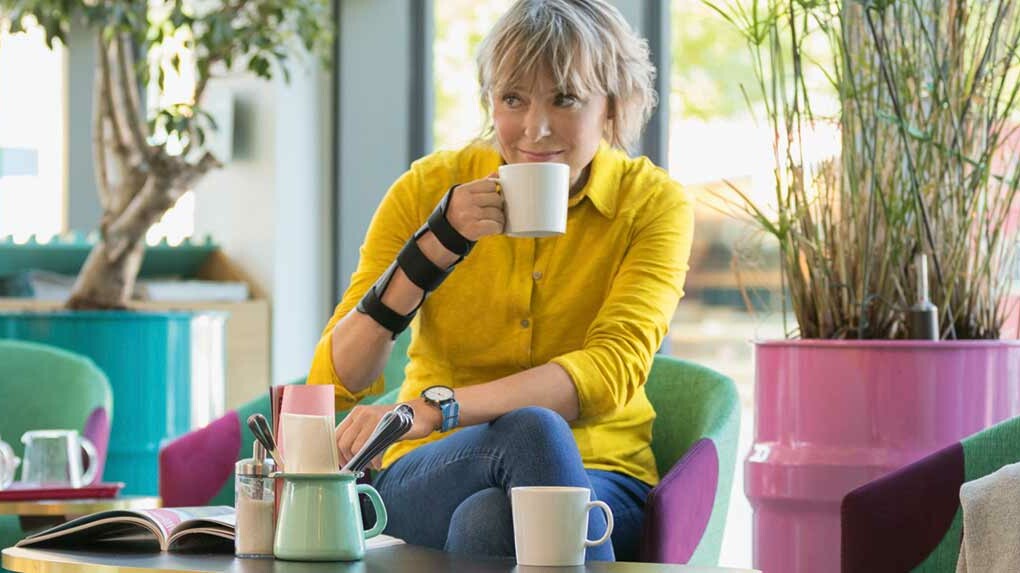 Frau trägt JuzoPro Manu Xtec Handgelenkorthese und hält eine Tasse in der Hand
