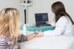 Eine Ärztin führt bei einer blonden Frau die Elektroneurografie durch. Hierfür ist das Gerät an dem Arm der Patientin angeschlossen.
