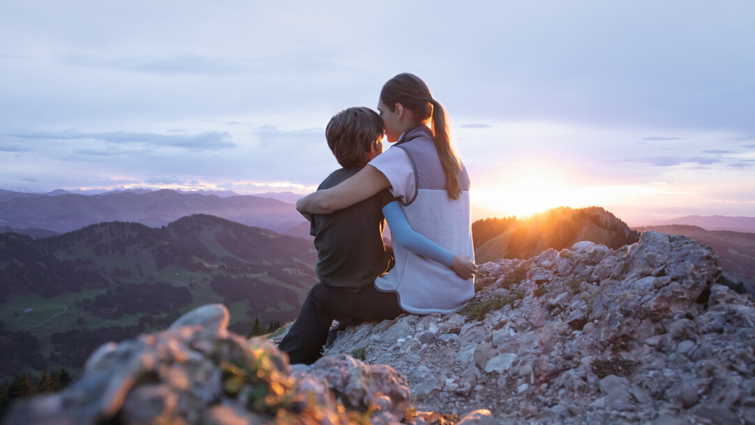 Une mère est assise avec son enfant au sommet d'une montagne. L'enfant porte une manchette de compression.