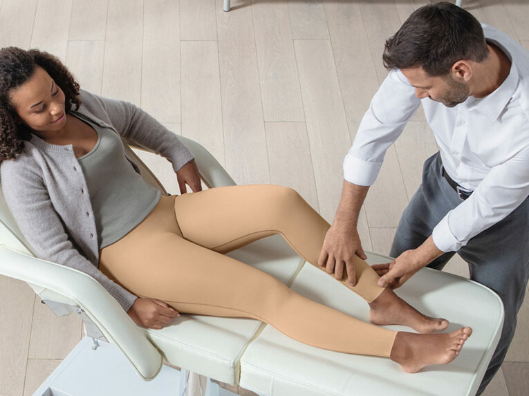 Ein Arzt überprüft bei einer Patientin den Sitz der Juzo Comprima Leggins