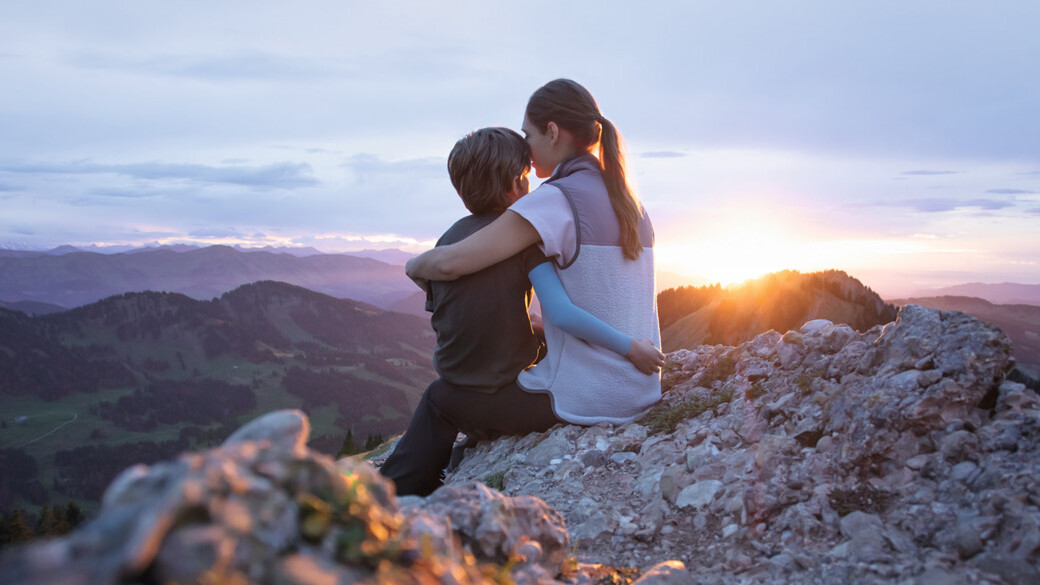 Una madre è seduta con il suo bambino sulla cima di una montagna. Il bambino indossa una manica a compressione. Una madre è seduta con il suo bambino sulla cima di una montagna. Il bambino indossa una manica a compressione.