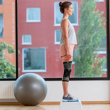 Una mujer está de pie con ambas piernas sobre una plataforma de step