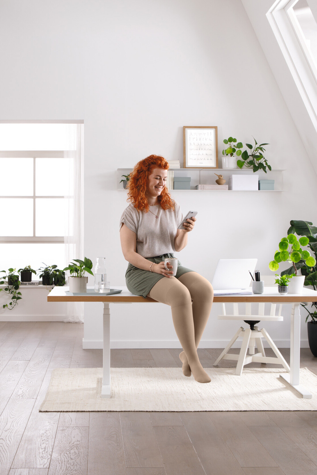 A woman is sitting at her desk, reading something on her mobile phone A woman is sitting at her desk, reading something on her mobile phone