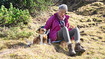 Woman and dog sitting on a hill.