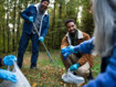 Drei Männer sammeln Plastikmüll in einem Wald