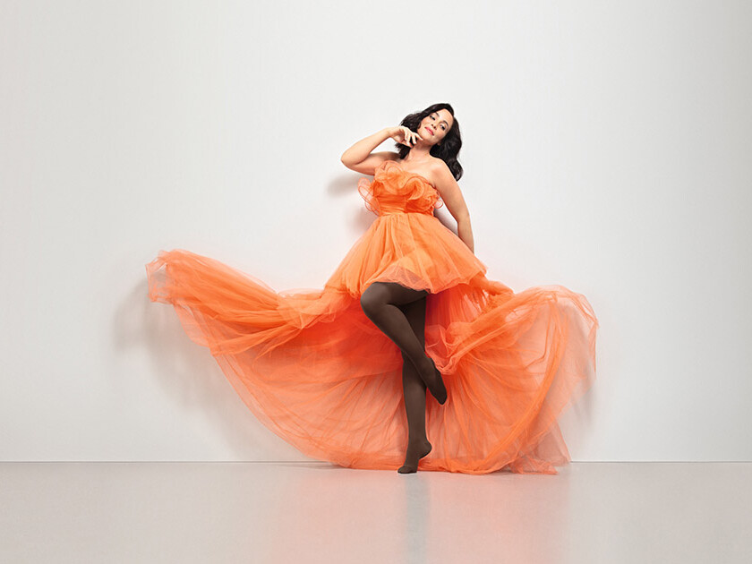 Mujer con vestido naranja. Lleva las medias marrones «Juzo Inspiration». Mujer con vestido naranja. Lleva las medias marrones «Juzo Inspiration».