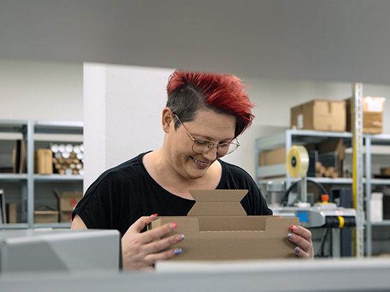 Mitarbeiterin im Logistikzentrum faltet einen Karton