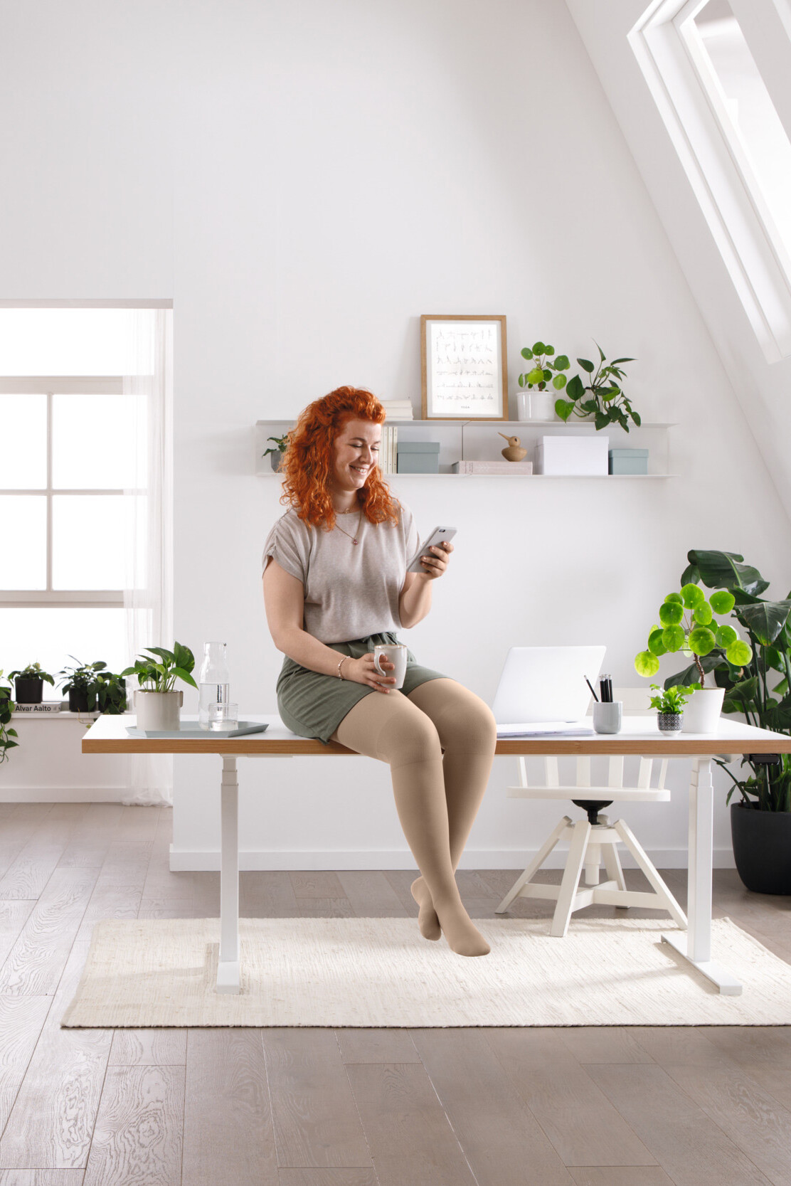 Une femme est assise à son bureau et lit quelque chose sur son téléphone portable Une femme est assise à son bureau et lit quelque chose sur son téléphone portable
