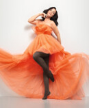 Mulher com Juzo Inspiration e collants em vestido cacau e laranja