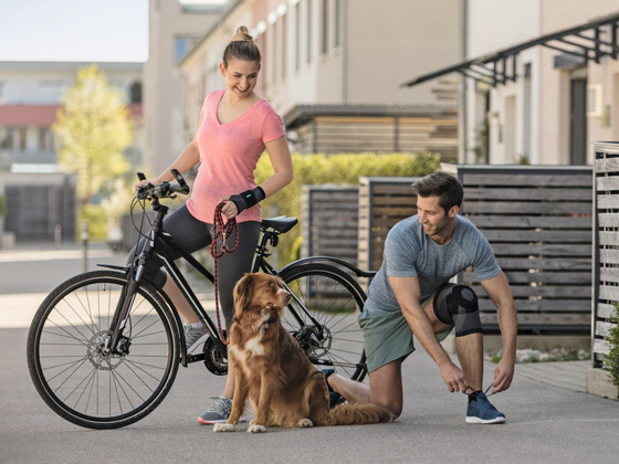 Una mujer y un hombre pasean un perro con una bicicleta