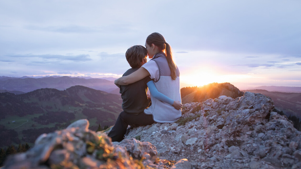 Traitement des cicatrices Une mère est assise avec son enfant au sommet d'une montagne. L'enfant porte une manchette de compression.