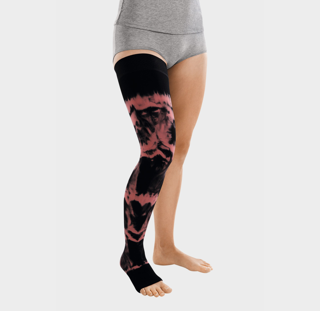 ScarComort Kompressionsstrumpf Schwarz-Rosa Frau trägt einen schwarzen ScarComfort Fine Kompressionsstrumpf mit rosafarbenem Batik-Muster