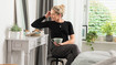 Mulher com camisola compressiva preta sentada num toucador com uma chávena de chá na mão