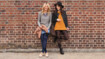 Two women leaning against a wall. They are wearing compression stockings with batik pattern