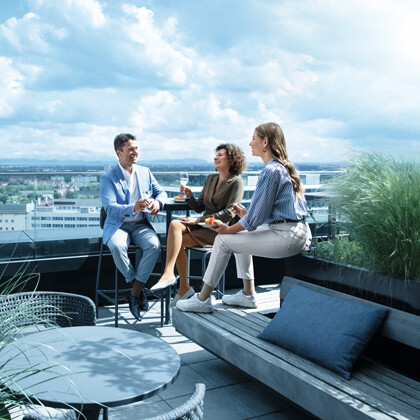 Ein Mann und zwei Frauen befinden sich auf einer Dachterasse und tragen Venenstrümpfe