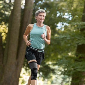 Frau im Wald beim Joggen mit Patella Xtex Plus Bandage