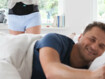 Ein Mann liegt im Bett mit einer Decke zugedeckt, im Hintergrund sieht man eine Lumbal Orthese von Juzo