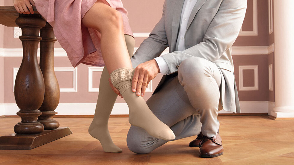 Un homme enfile un bas de contention à une femme. Le décor a un air de conte de fées, comme dans Cendrillon. Un homme enfile un bas de contention à une femme. Le décor a un air de conte de fées, comme dans Cendrillon.