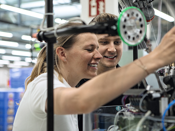 Eine Frau und ein Mann betrachten eine Strickmaschine