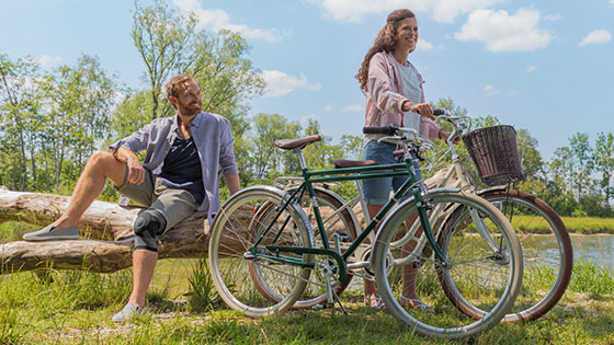 Bandager A couple is travelling by bike. The man is wearing a knee support.