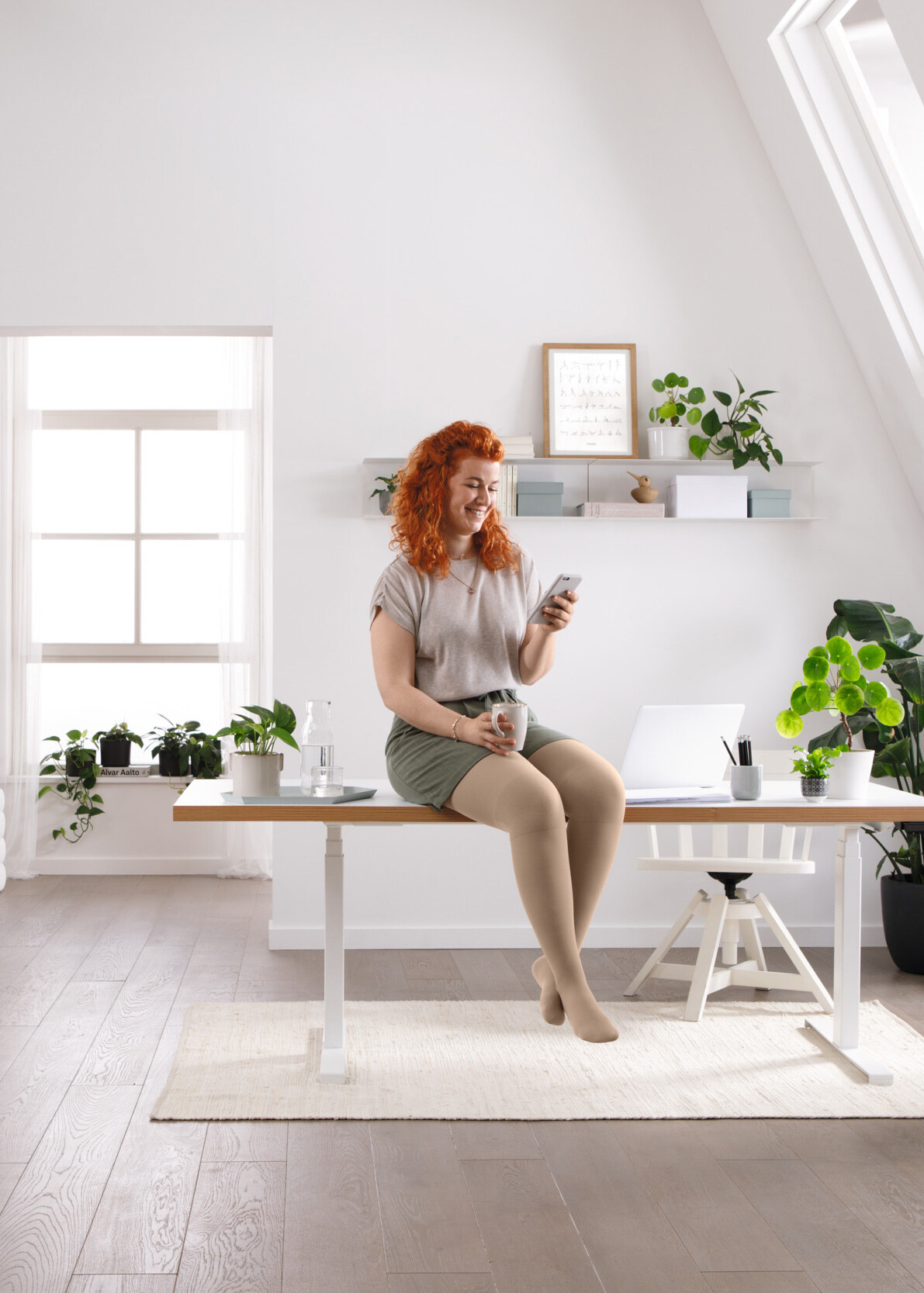 En kvinna sitter vid sitt skrivbord och läser något på sin mobil