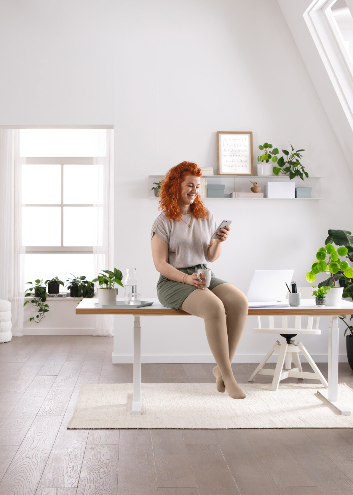 Une femme est assise à son bureau et lit quelque chose sur son téléphone portable