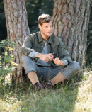 1. Zdjęcie lifestyle Juzo Adventure Mężczyzna noszący Juzo Adventure, siedzący pod drzewem i krojący jabłko