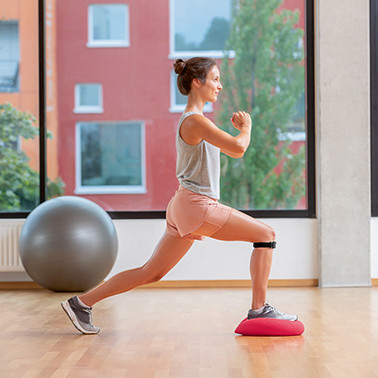 Exercise Split squats Step 1 A woman doing a lunge forwards on a soft cushion