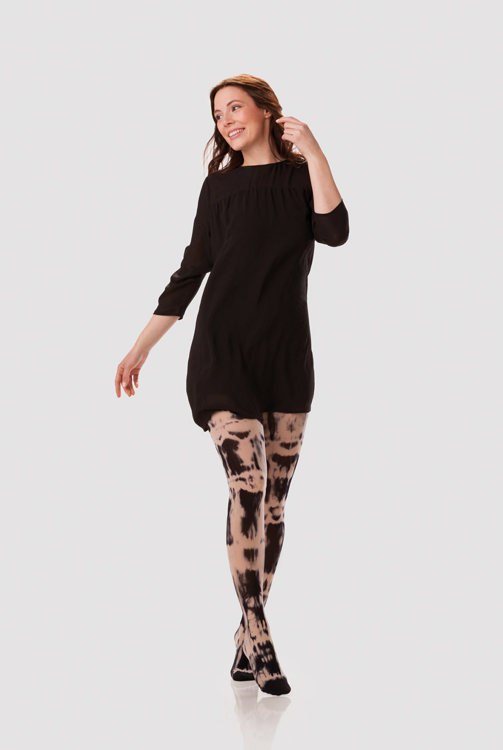 Eine Frau trägt ein schwarzes Langarmkleid mit einer Kompressionsversorgung in Batik Schwarz-Sesam Eine Frau trägt ein schwarzes Langarmkleid mit einer Kompressionsversorgung in Batik Schwarz-Sesam