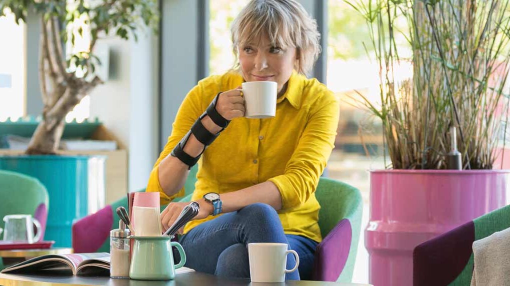 Une femme porte une orthèse de poignet JuzoPro Manu Xtec et tient une tasse à la main Une femme porte une orthèse de poignet JuzoPro Manu Xtec et tient une tasse à la main