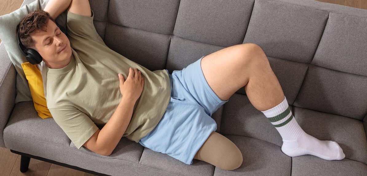Juzo Classic Seamless stumpstrømpe Ung mand bærer den patenterede Juzo Classic Seamless stumpstrømpe, mens han ligger på sofaen uden protese