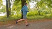 Mann joggt durch Wald und trägt ein Patellasehnenband