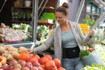 Eine Frau mit Rückenorthese kauft frisches Gemüse auf dem Markt