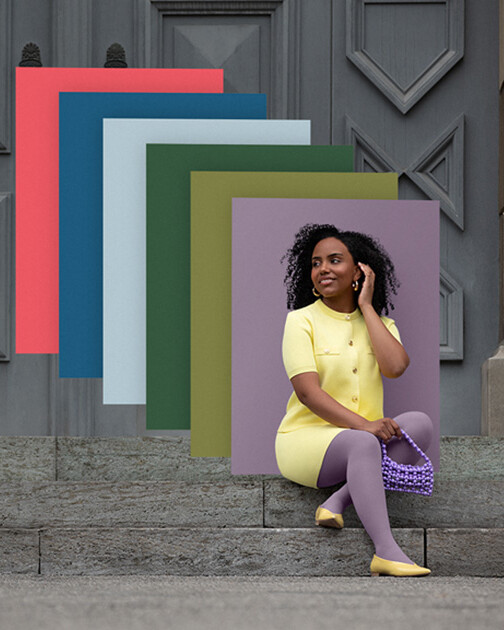 Una mujer con medias de compresión en color Cozy Violet está sentada en unas escaleras. Al fondo, los paneles de color de la actual colección Juzo Trend Colours. Una mujer con medias de compresión en color Cozy Violet está sentada en unas escaleras. Al fondo, los paneles de color de la actual colección Juzo Trend Colours.