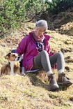 Frau in Juzo Dynamic Strümpfen sitzt mit ihrem Hund auf einem Berg