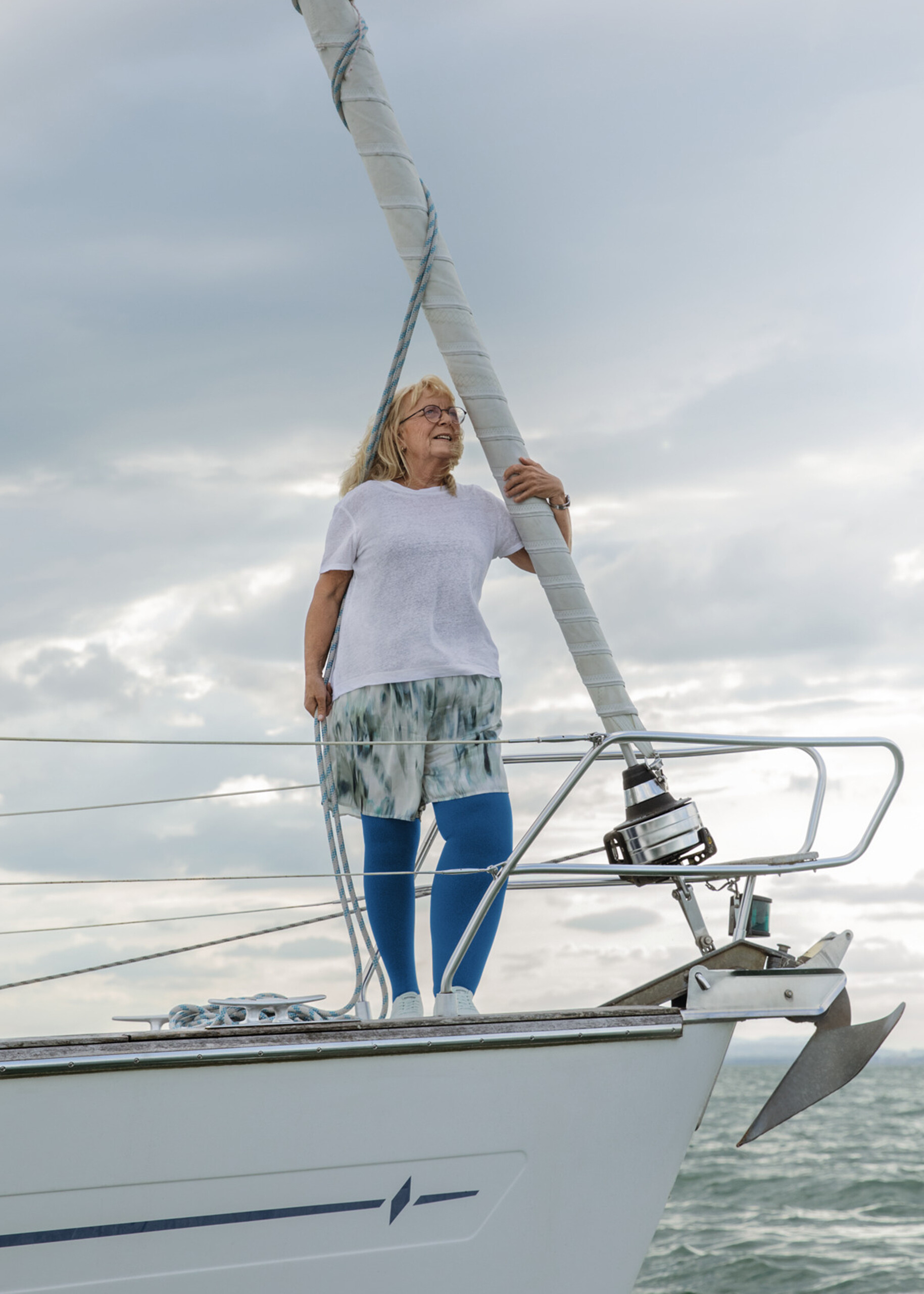Eine Frau steht auf einem Boot. Sie hat ein Lymphödem am Bein und trägt blaue Kompressionsstrümpfe