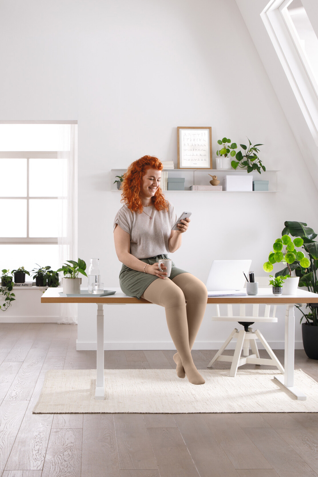Eine Frau sitzt auf ihrem Schreibisch und liest etwas auf ihrem Handy Eine Frau sitzt auf ihrem Schreibisch und liest etwas auf ihrem Handy