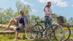 Mann und Frau mit Fahrrädern am Ufer eines Sees